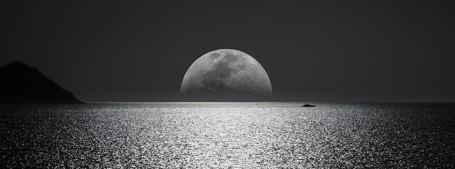 white and black moon with black skies and body of water photography during night time
